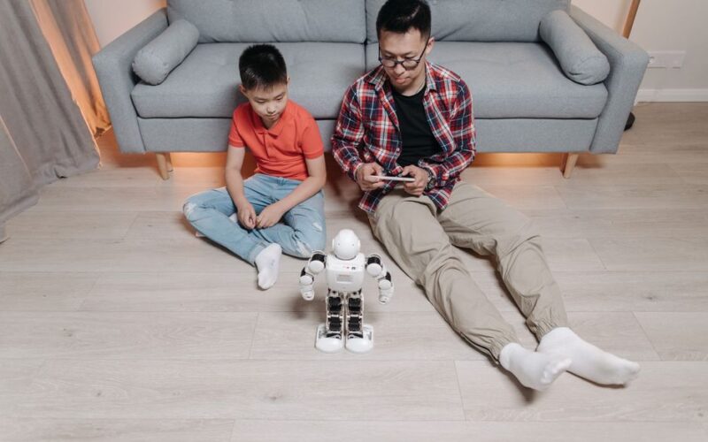 Father and son bonding over robotics and technology at home, enjoying playful interaction with a robot.