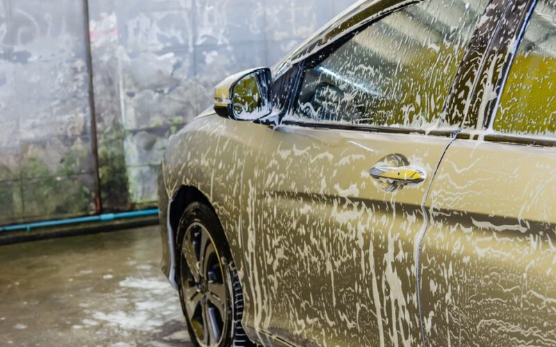 A car being washed with soap at a car wash service, highlighting cleaning and care.