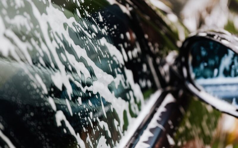 Detailed view of car covered in soapy foam during a wash, highlighting cleanliness.