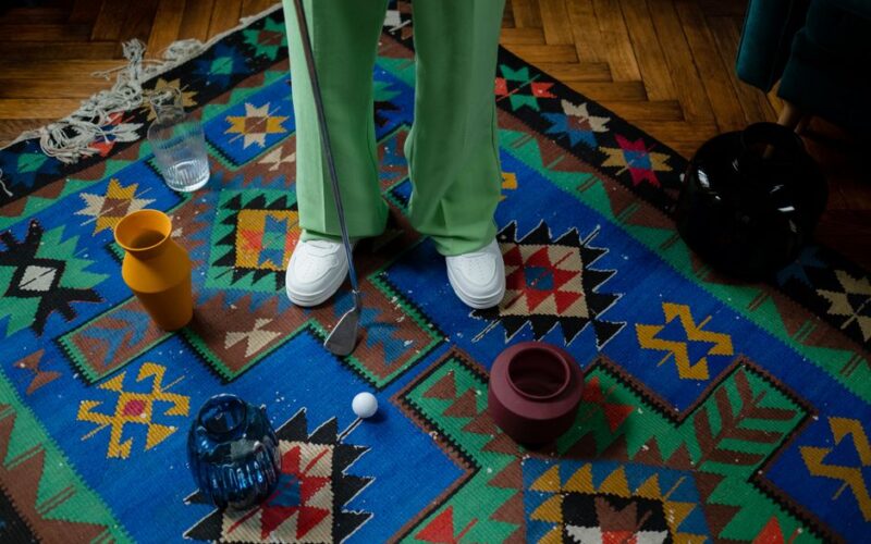 Playful golf scene on a vibrant patterned carpet, surrounded by colorful vases and decor.