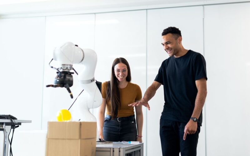 Two engineers collaborating on testing a futuristic robotic prototype in a modern indoor lab.