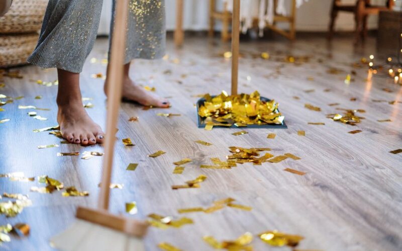 Woman cleaning up confetti after a party at home, symbolizing tidiness and chores.