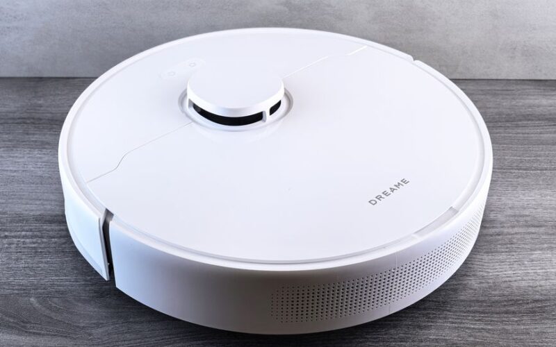 High-angle view of a sleek white robotic vacuum cleaner on a wooden floor, perfect for smart home setups.