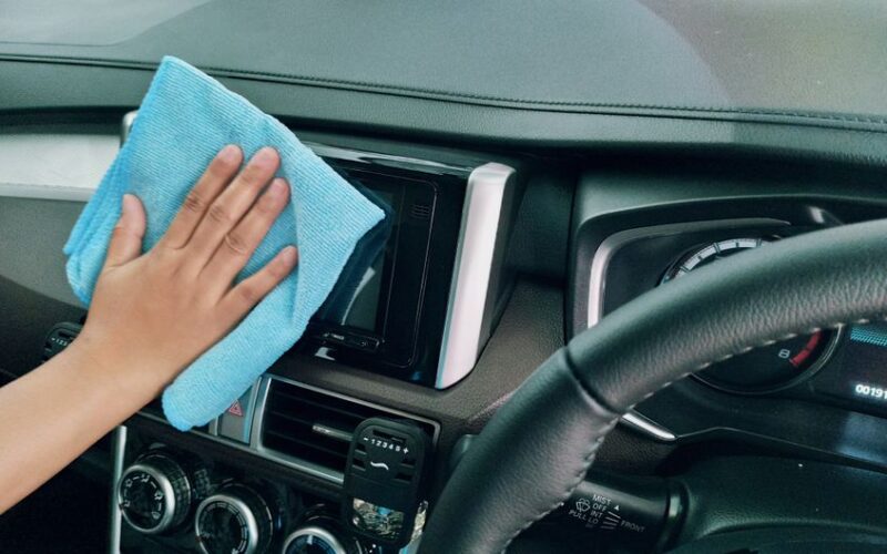 Crop anonymous person polishing panel in right hand drive car by using blue fiber cloth