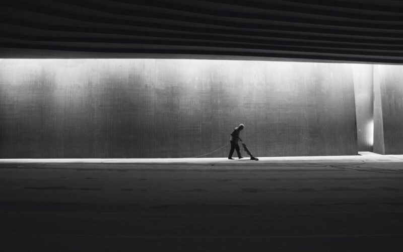 Silhouette of a person cleaning an interior space, showcasing solitude in a modern urban environment.