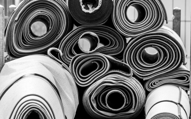 Artistic black and white photo of stacked rolled carpets showcasing textures.