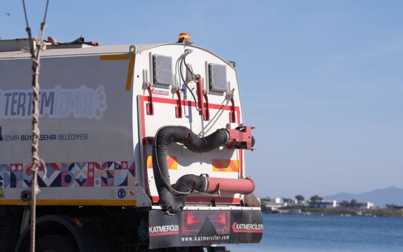 Street cleaning truck by the coastal road in Foça, İzmir, Türkiye, with clear blue sky in the background.