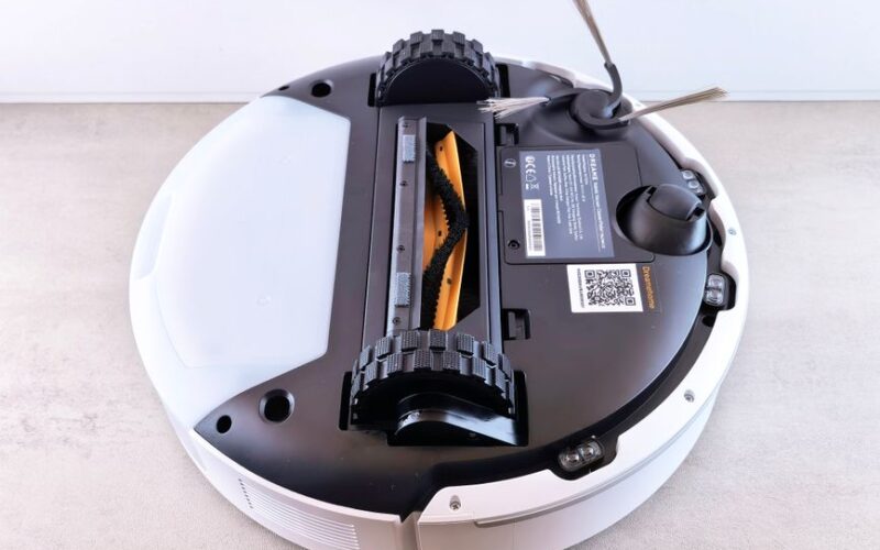 Close-up view of a robotic vacuum cleaner's underside displaying brushes and sensors.