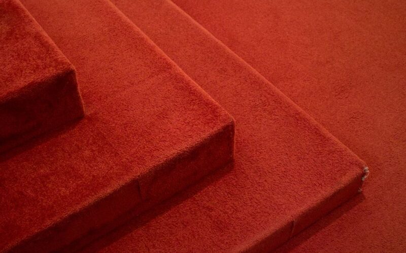 Detailed view of red carpeted stairs, highlighting texture and design.