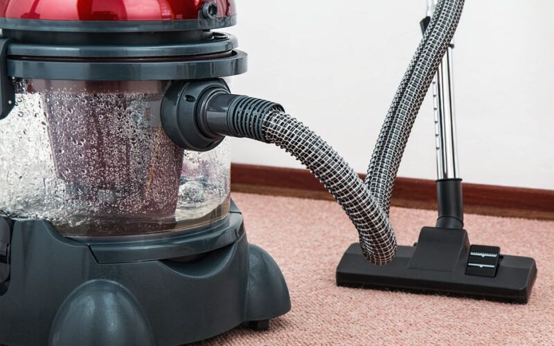 Close-up of a modern vacuum cleaner with water filtration on carpet floor indoors.