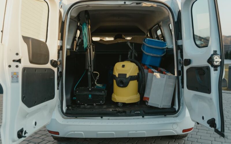A van with cleaning supplies reveals its open trunk filled with tools and equipment.