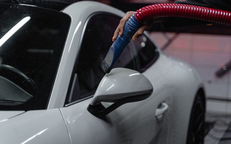 A white sports car is meticulously vacuumed indoors for a flawless shine and maintenance.