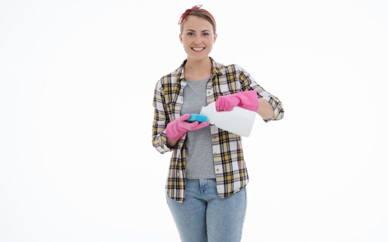 Young woman smiling while cleaning with gloves, showcasing a positive approach to housekeeping.