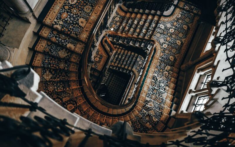 A stunning spiral staircase adorned with intricate carpet patterns and elegant railings.