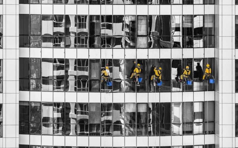 High-rise window cleaners in Dubai cleaning a skyscraper, showcasing urban architecture.