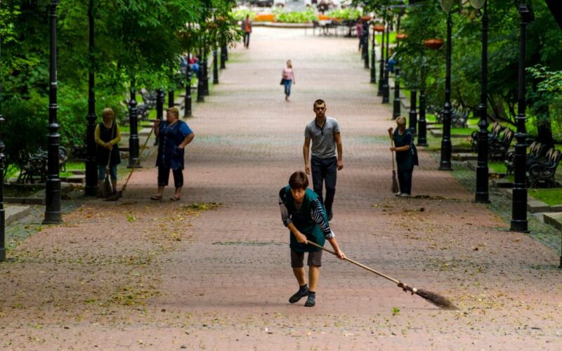 People cleaning and walking in a lush green park in Lviv, Ukraine.