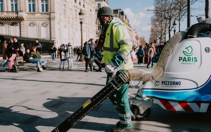 Paris street cleaner operating equipment, showcasing urban cleanliness amidst city life.