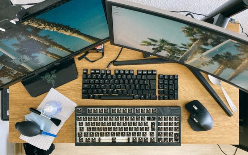From above of desktop with multi monitors and keyboard with remove keycaps for cleaning
