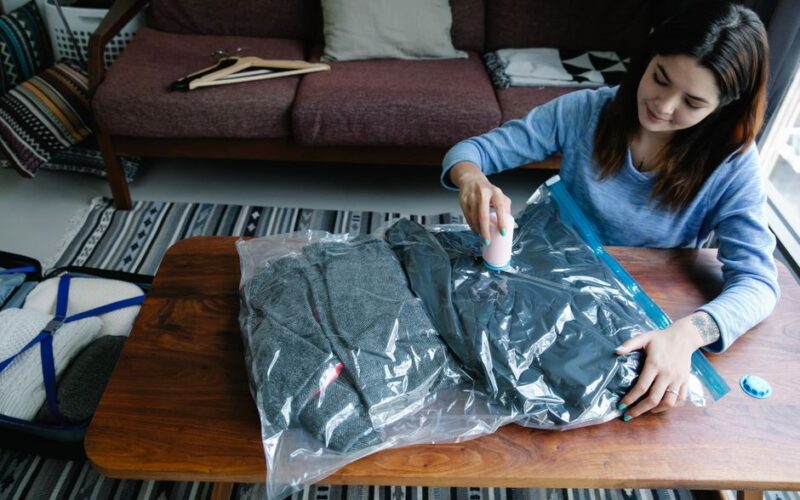 Woman sealing clothes in vacuum bags for efficient packing at home.