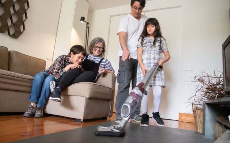 A family sharing a fun moment while vacuuming together in the living room.
