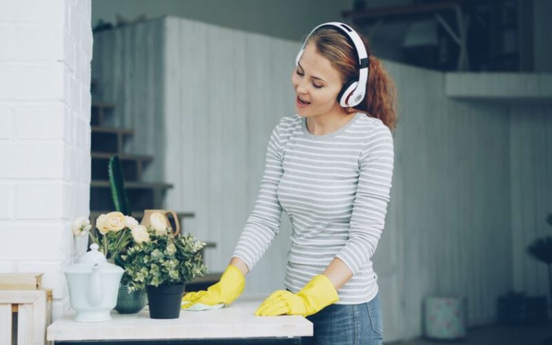 A woman enjoying cleaning with headphones on, adding a touch of joy to chores.