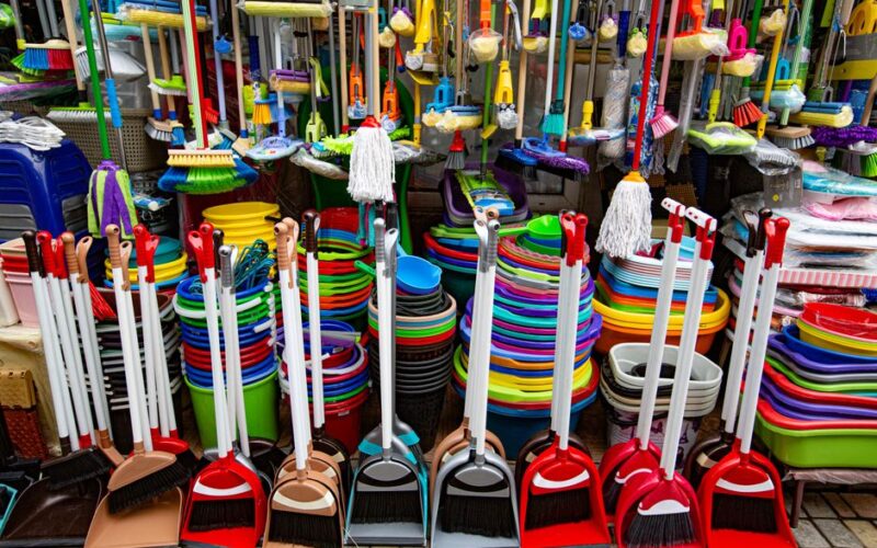 From above various sets of broom and scoop placed in household goods store near colorful basins and bins