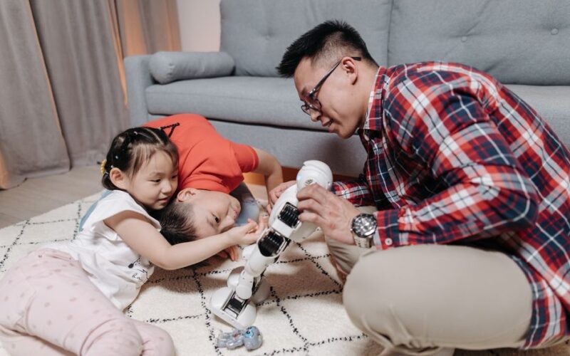 Family bonding time with a father and kids playing creatively with a robot toy.