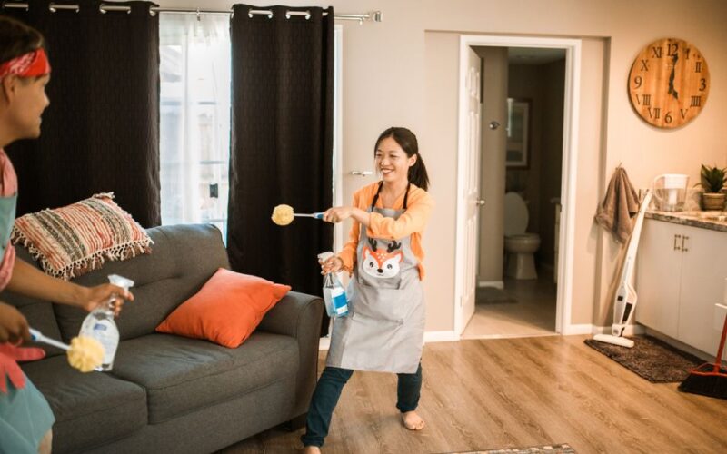 A cheerful couple engages in a playful cleaning session in their home.