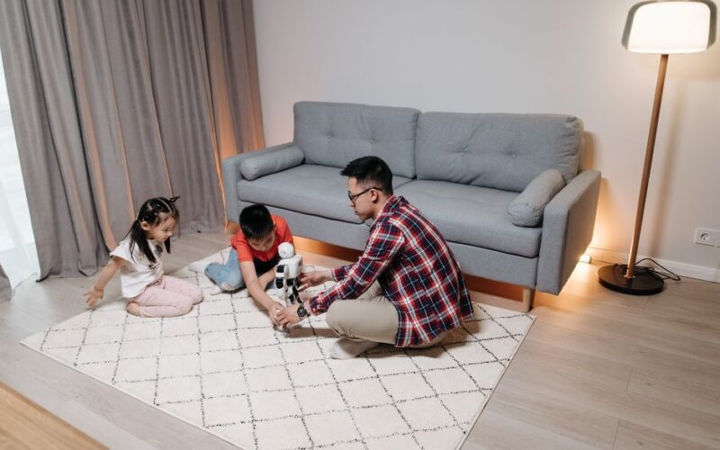 Father and children playing with a robot toy in a cozy indoor setting.