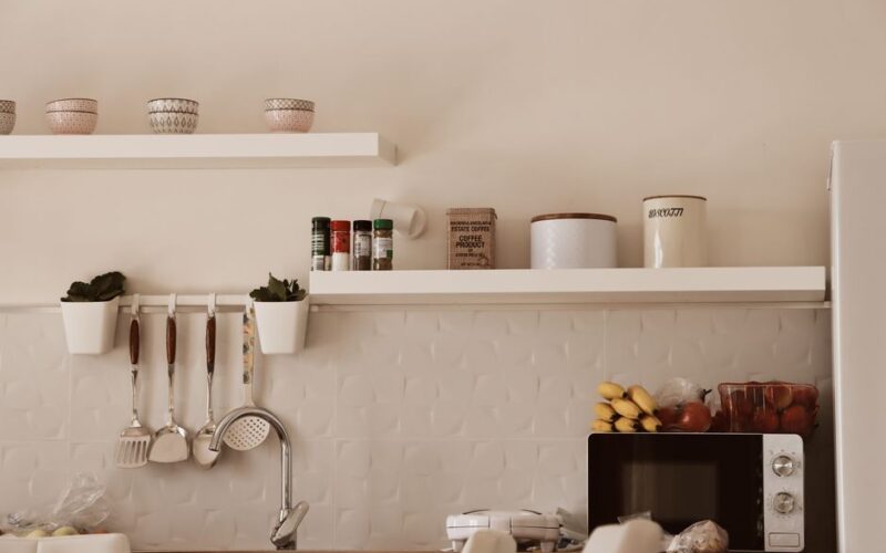 Stylish modern kitchen with minimalist shelves and appliances in warm tones.