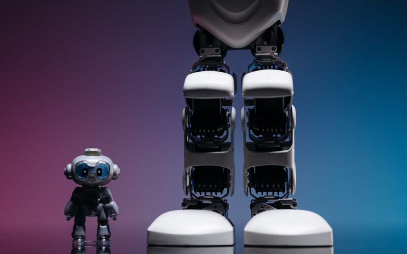 A large robot stands beside a small toy robot with colorful studio lighting, showcasing technology innovation.