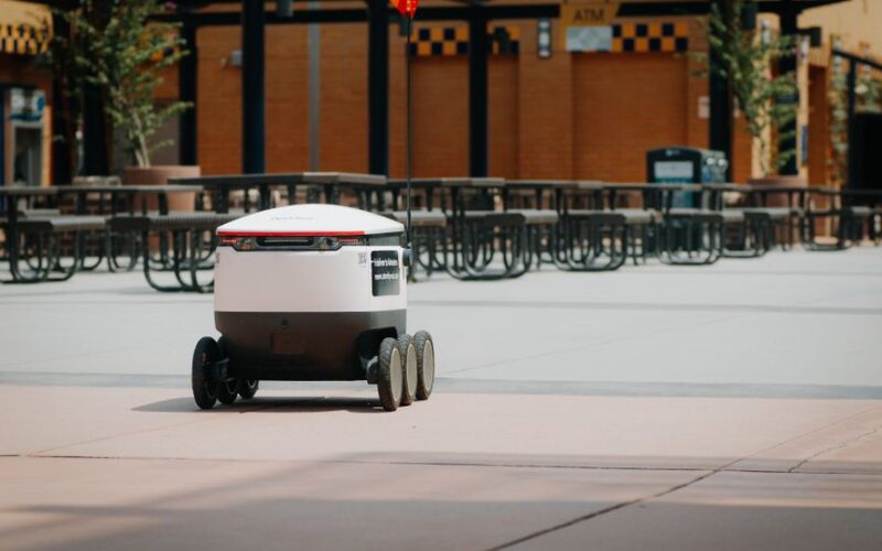 Futuristic delivery robot navigating an empty outdoor plaza, symbolizing modern innovation and mobility.