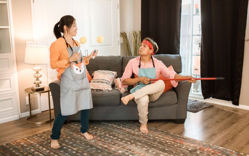 A man and woman enjoying a fun cleaning session in their living room.