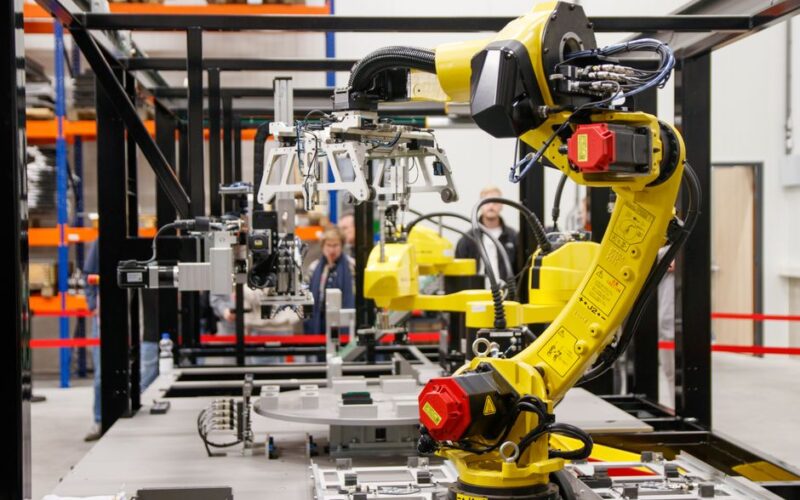 Close-up of a yellow industrial robotic arm in action at a modern manufacturing facility.