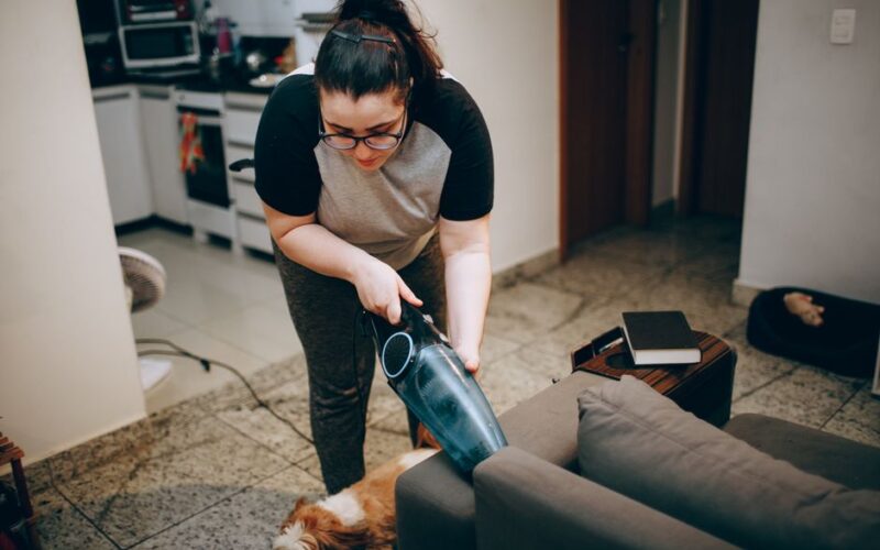 Woman cleaning a living room with a vacuum, showing a cozy and tidy home environment.