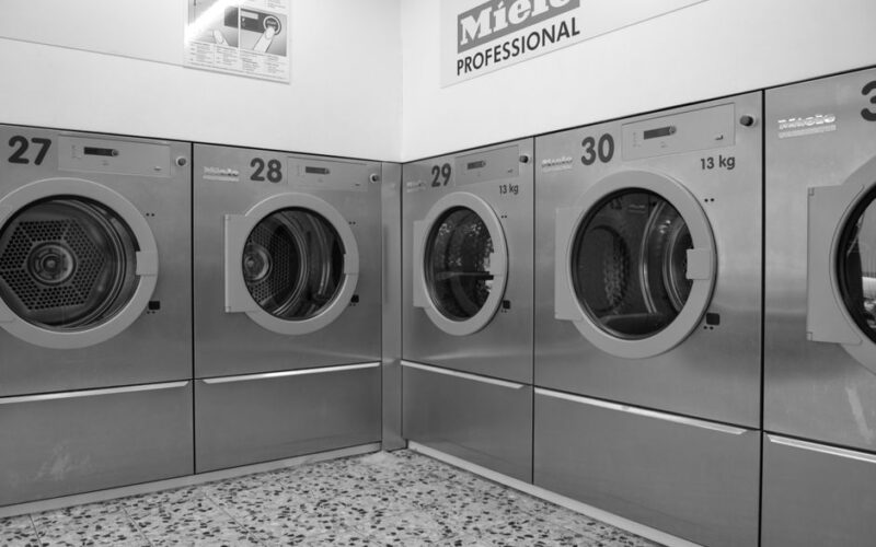 A sleek row of industrial washing machines in a modern laundromat, conveying efficiency and cleanliness.
