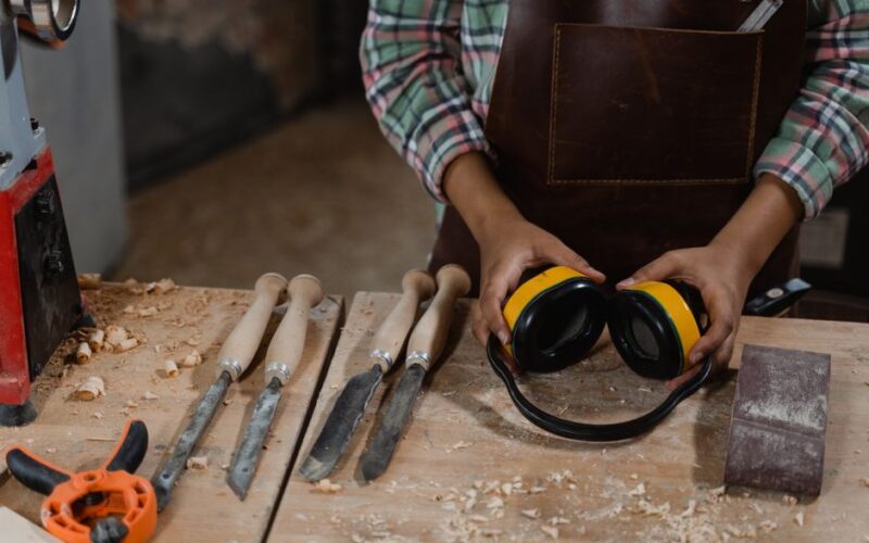 A woodworker prepares tools and equipment in a dusty workshop, demonstrating craftsmanship.
