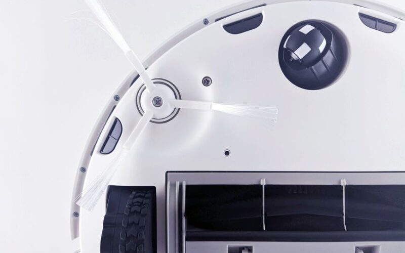 Close-up of a modern robotic vacuum cleaner underside showing brushes and components.