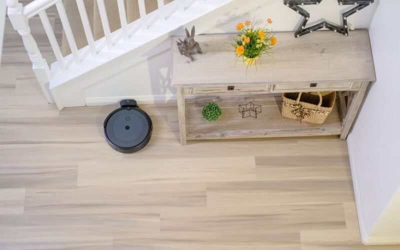 An autonomous robovac cleaning a wooden floor next to a decorative console table.