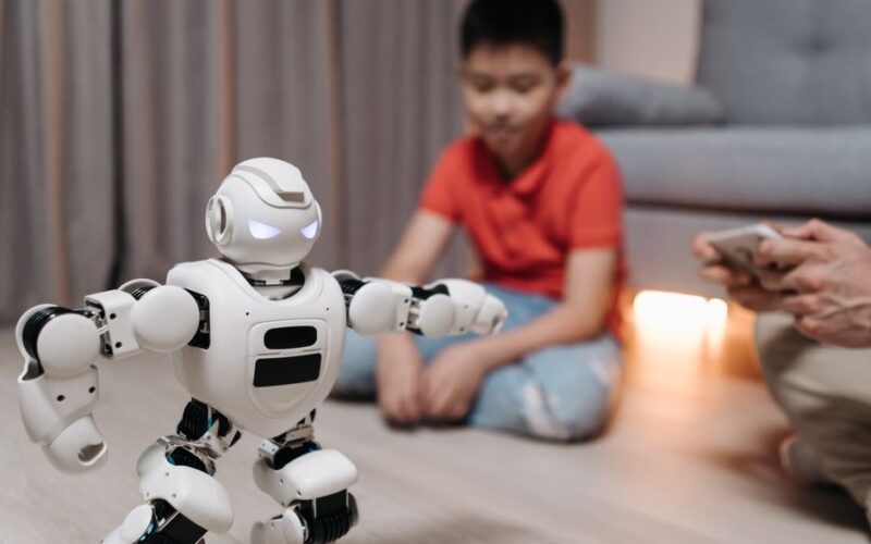 A young boy interacts with a programmable robot in a cozy living room setting.