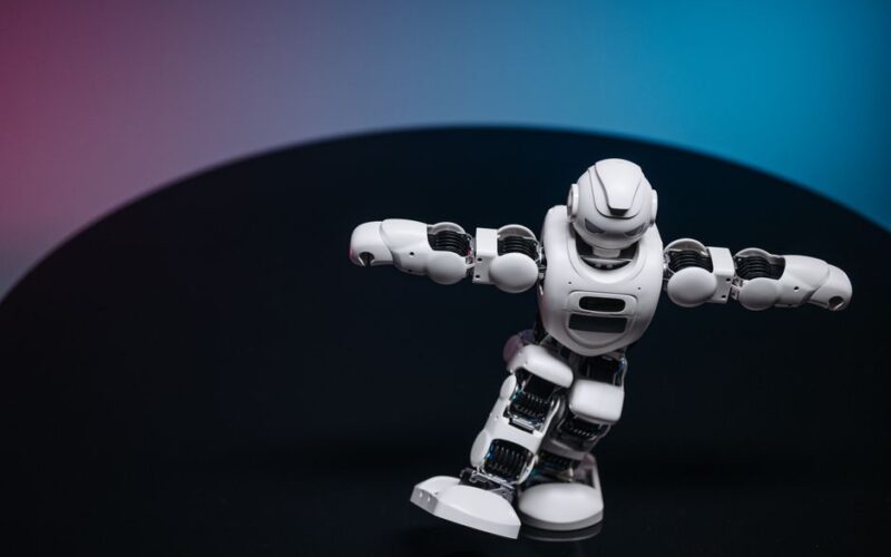 A futuristic white robot toy performing on a sleek dark surface.