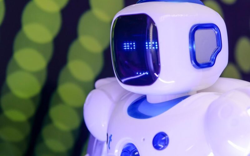 Close-up of a modern humanoid robot with glowing blue features on a green abstract background.