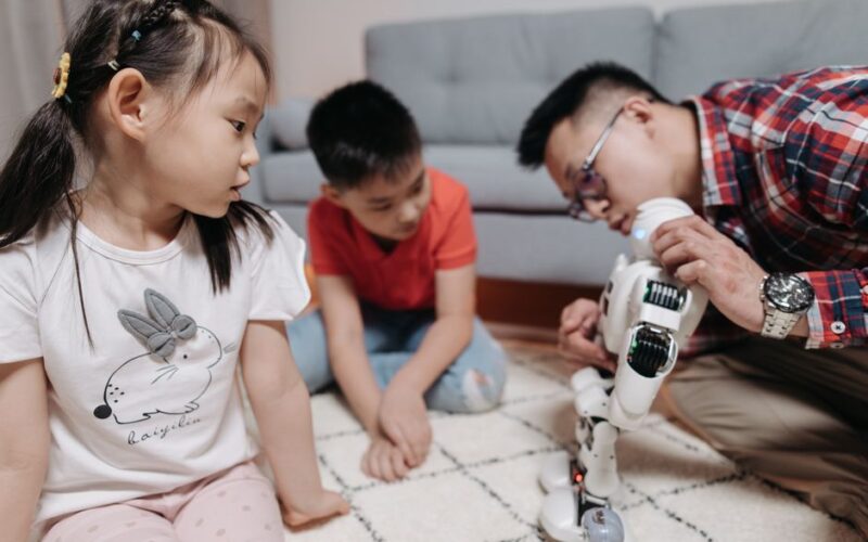 Father and children enjoying creative playtime with a robot indoors.