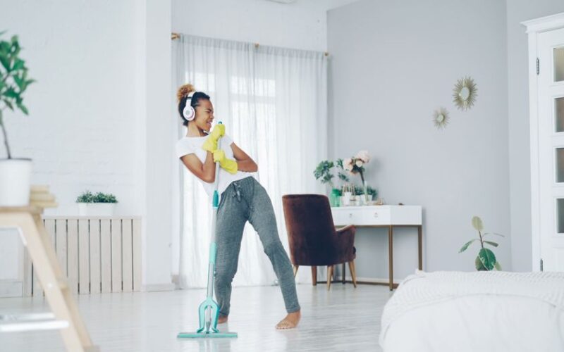 Happy woman cleaning her home while listening to music, enjoying the process.
