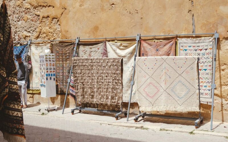 Traditional Moroccan rugs on display against an ancient wall in El Jadida, Morocco.