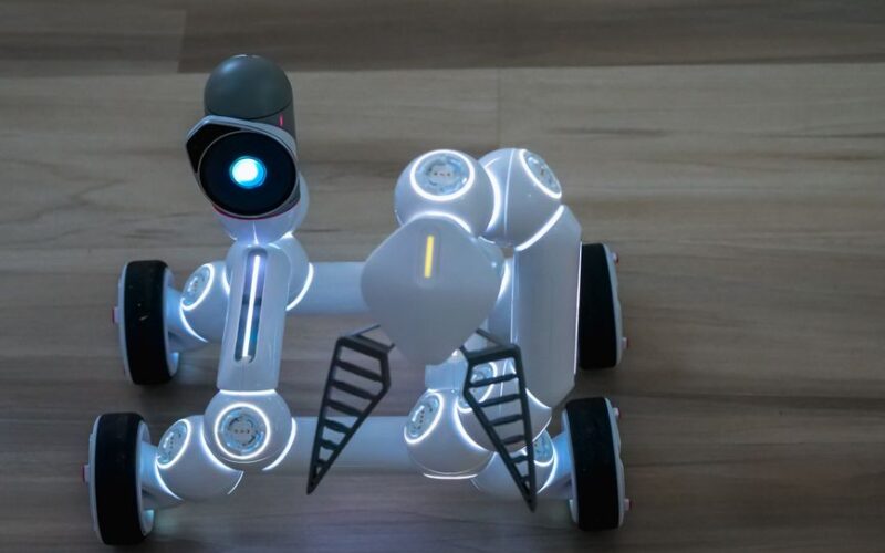 Close-up of a wheeled robot toy on a wooden surface indoors.
