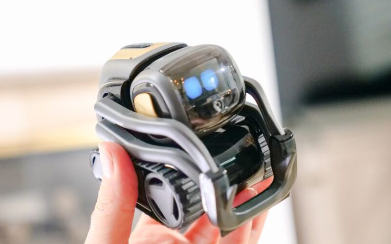A close-up view of a hand holding a small, modern robot, showcasing innovation in robotics.