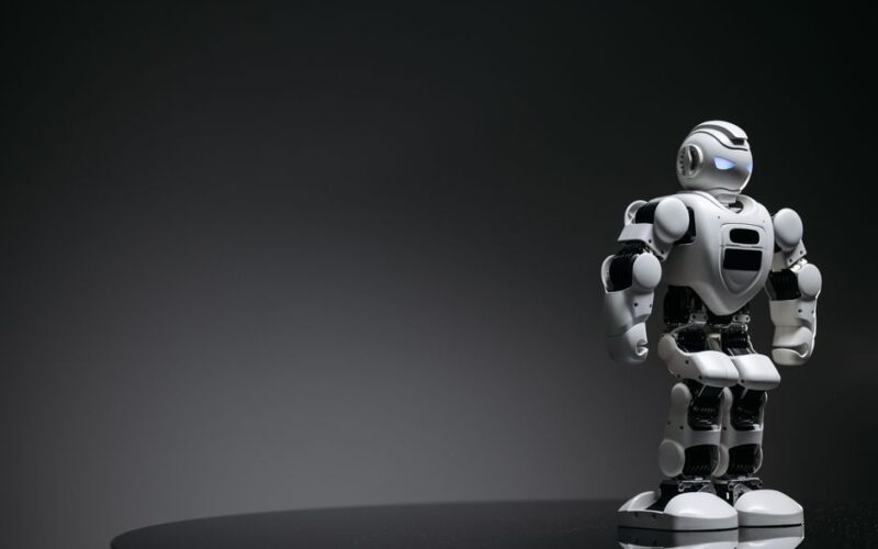 Compact humanoid robot toy standing on a reflective surface, exuding a futuristic vibe.