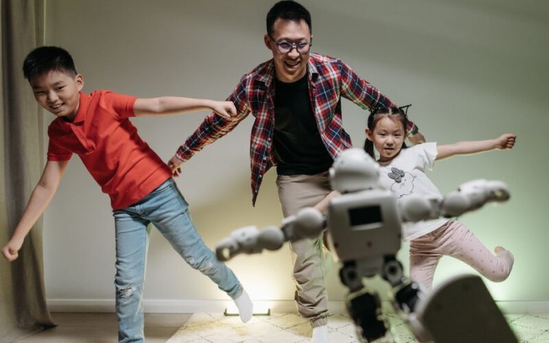 Asian family enjoying playtime with a dancing robot, showcasing joy and technology indoors.