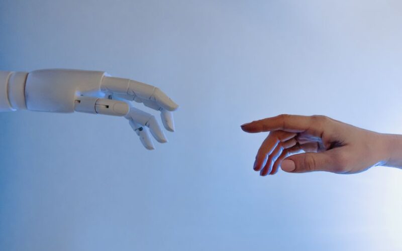 A human hand reaching towards a robotic hand symbolizing technology and connection.